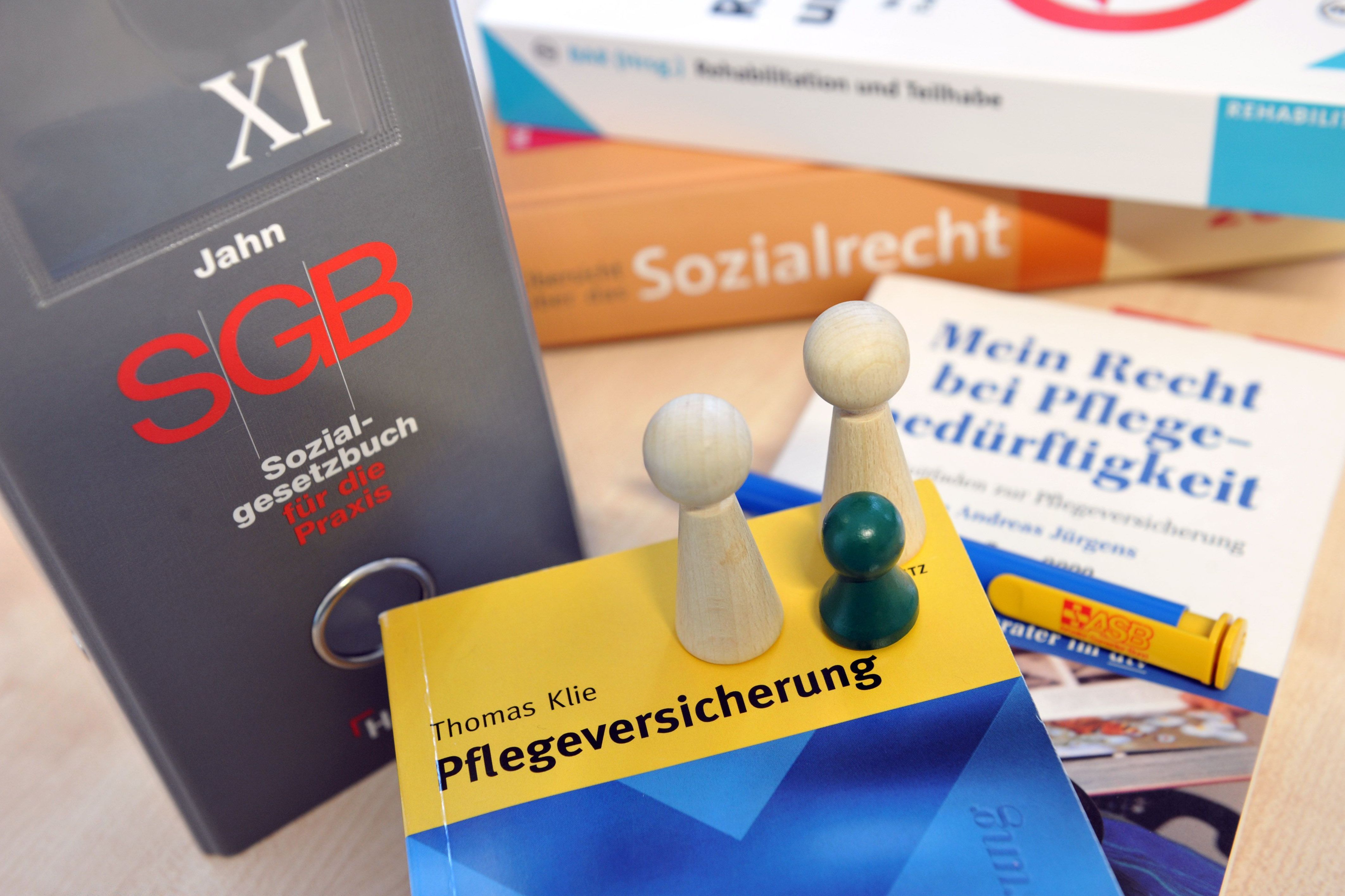 Mehrere Publikationen zum Thema Pflegeversicherung sowie eine Ausgabe des Sozialgesetzbuchs liegen auf einem Tisch