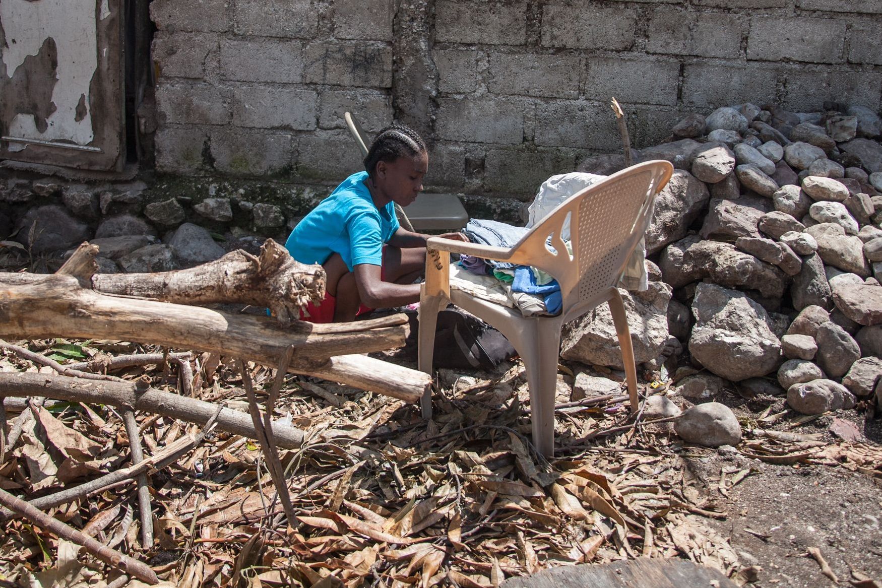 Ein Mädchen sitzt vor ihrem zerstörten Elternhaus in Haiti auf dem Boden