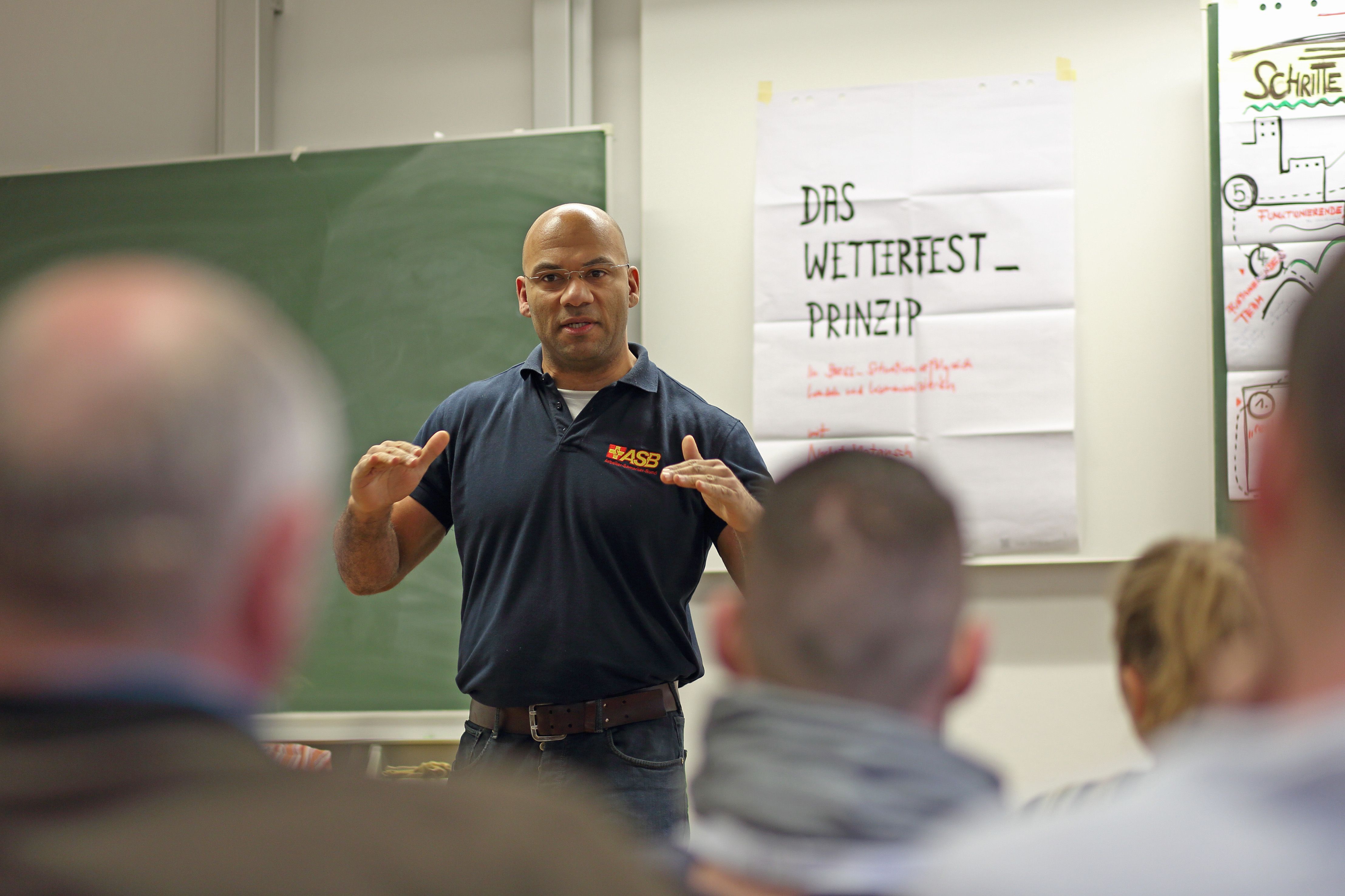 Seminar Wetterfest - deeskalierende Kommunikation mit Samuel Meffire Dozent Samuel Meffire vor Teilnehmern des Seminars
