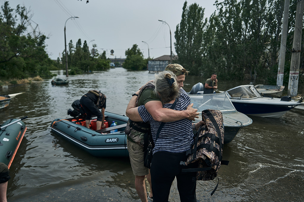 Eine Frau umarmt einen Freiwilligen, der ihr geholfen hat, in einem Schlauchboot aus einem überfluteten Viertel in Cherson, Ukraine, evakuiert zu werden.
