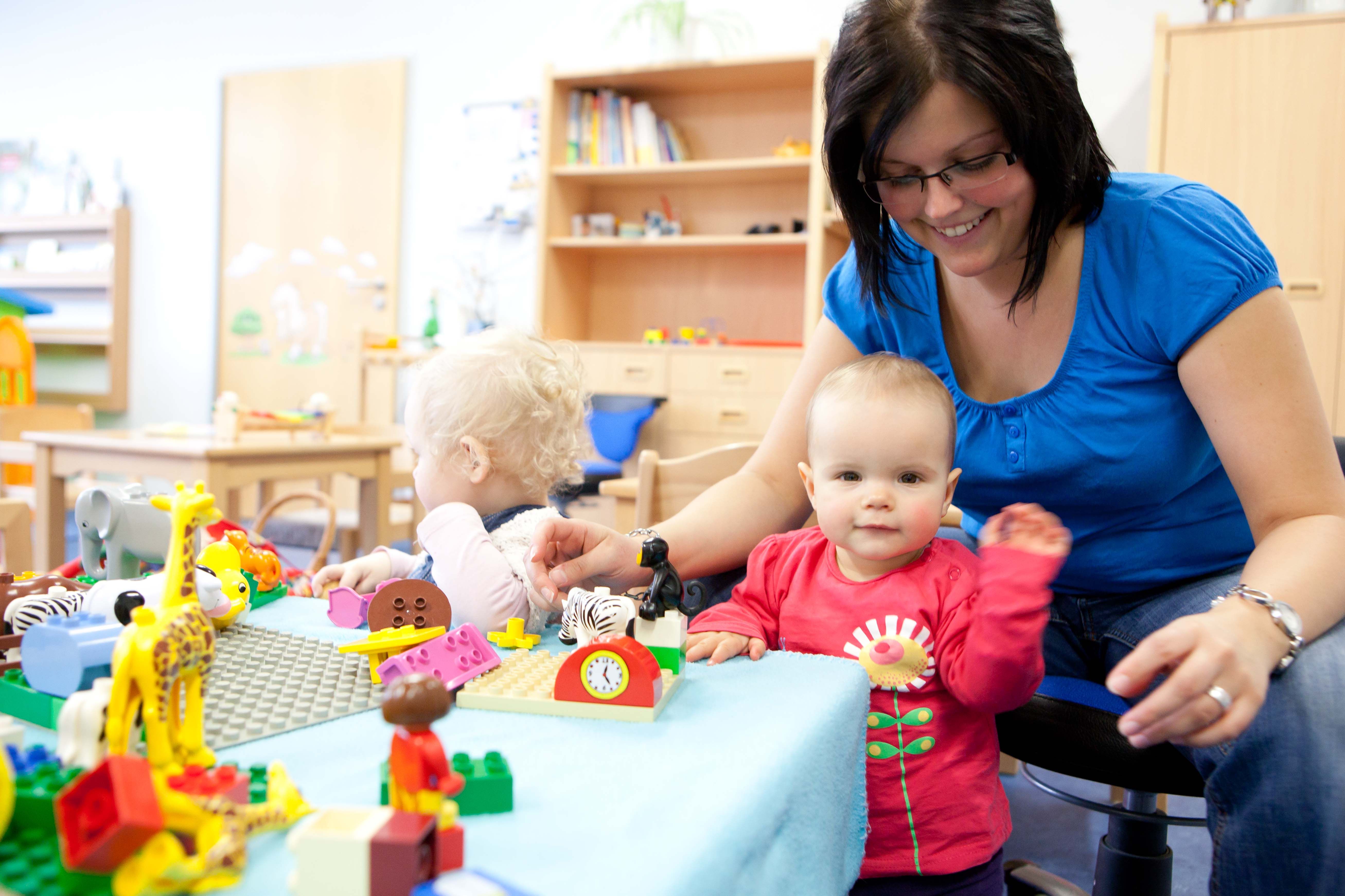 kinderkrippe-erzieherin-laechelt-kleinkind-an