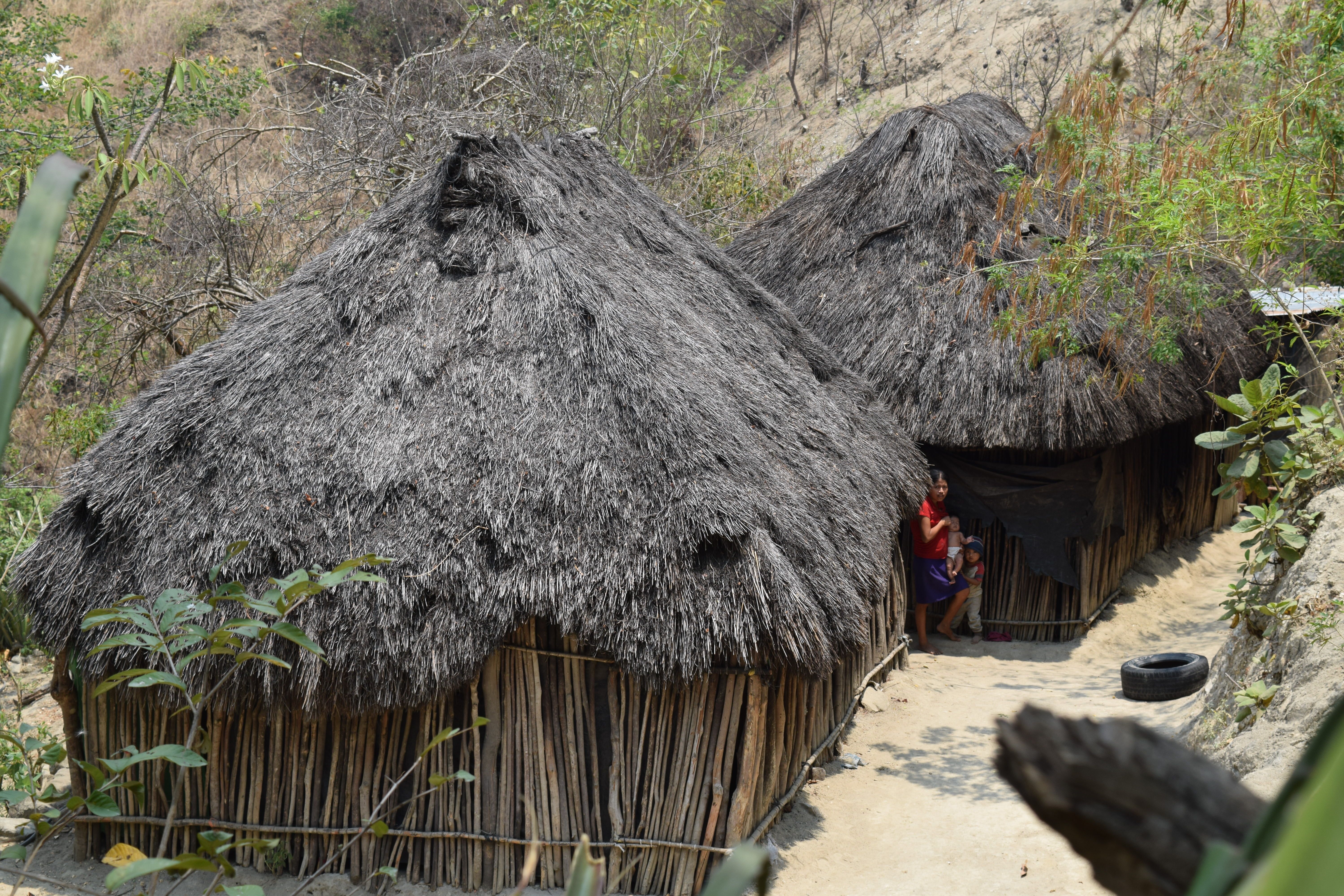 Muter mit zwei Kindern vor einer einfachen Holzhütte in Guatemala