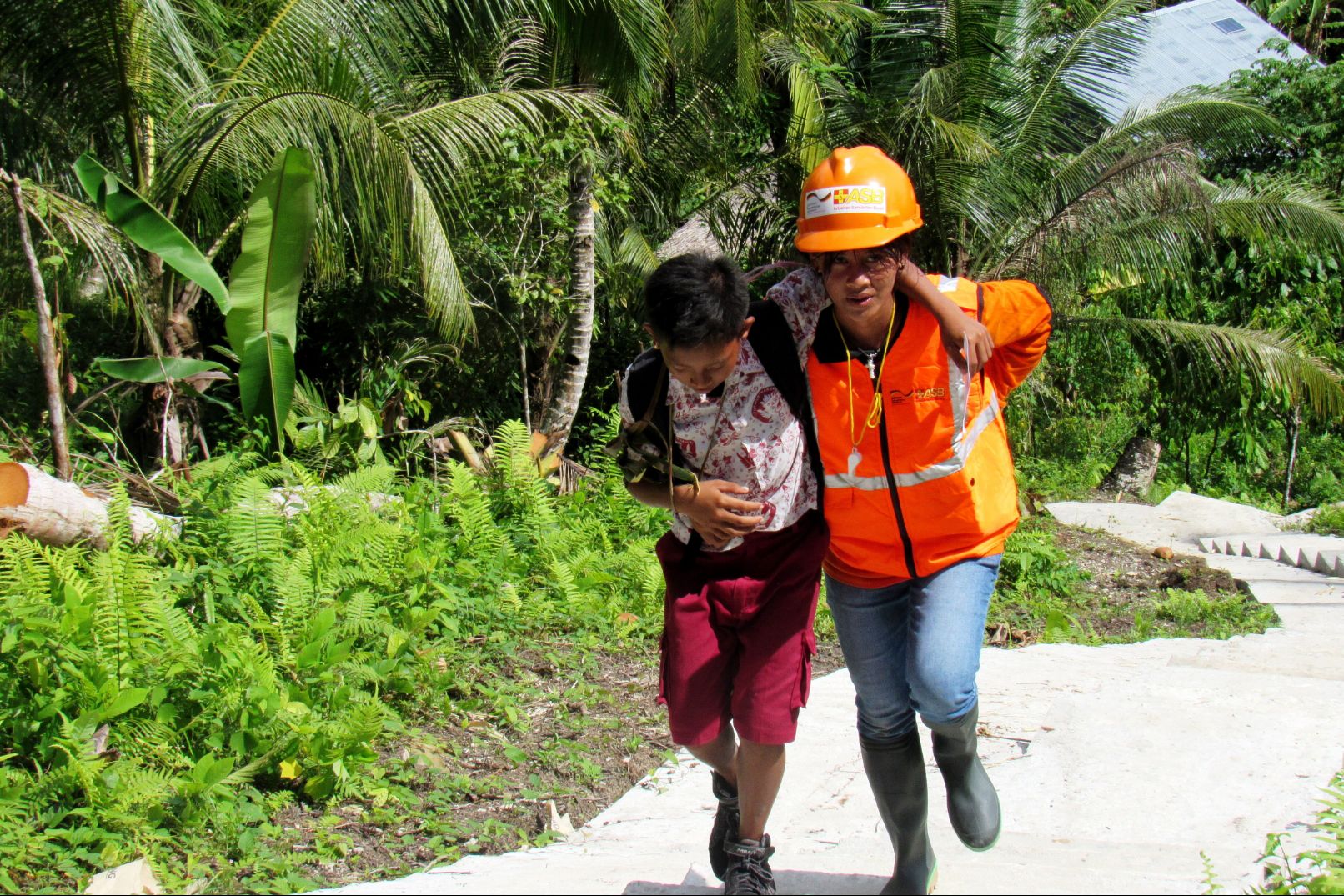 Ein Helfer hilft einem gehbehinderten Mann, sich vor einem Erdbeben in Sicherheit zu bringen - bei einer Übung auf den Mentawai-Inseln