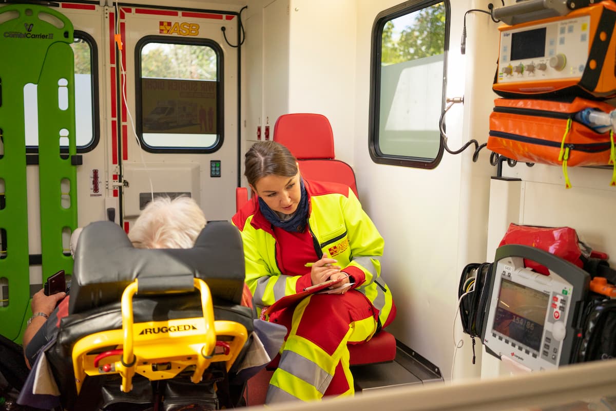 Angehende Notfallsanitätering im Rettungswagen beim Gespräch mit einem Patienten. Fitness und Verantwortungsbewusstsein sind wichtige Voraussetzungen für diesen Beruf.