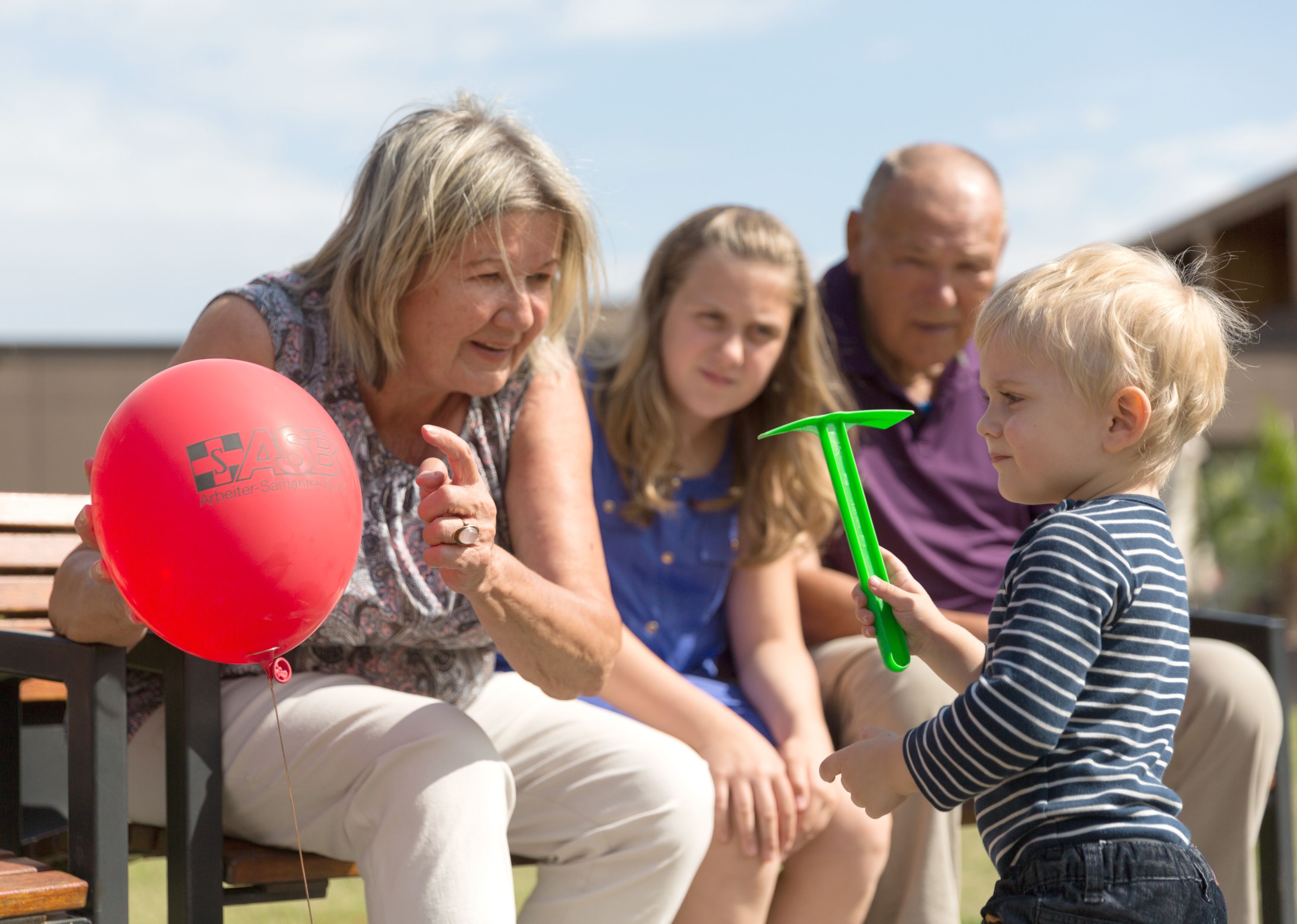 Mehrere Kinder, Erwachsene und Senioren in einem Kinderspielzimmer, die gemeinsam lachen.