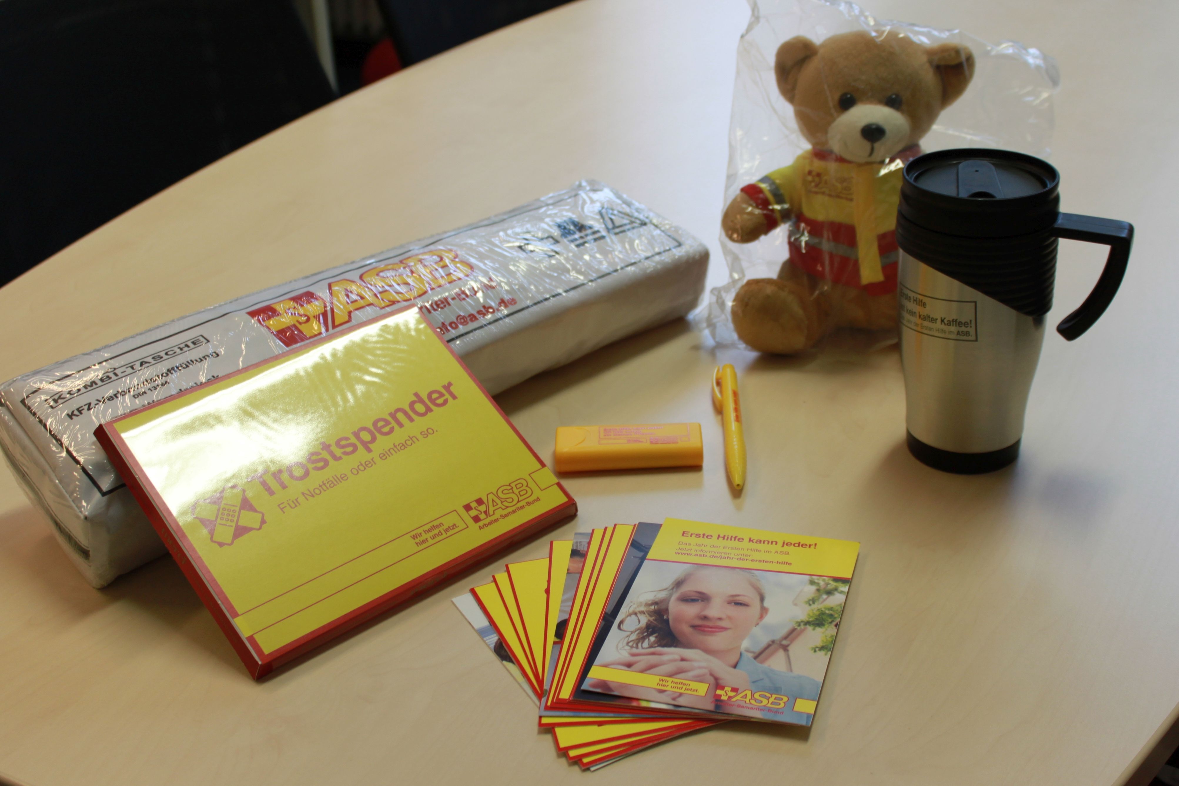 ehkannjeder-gewinnerpaket.jpg Erste-Hilfe-Kombitasche, Thermobecher, ASB-Teddy, Pflaster und Trostschokolade
