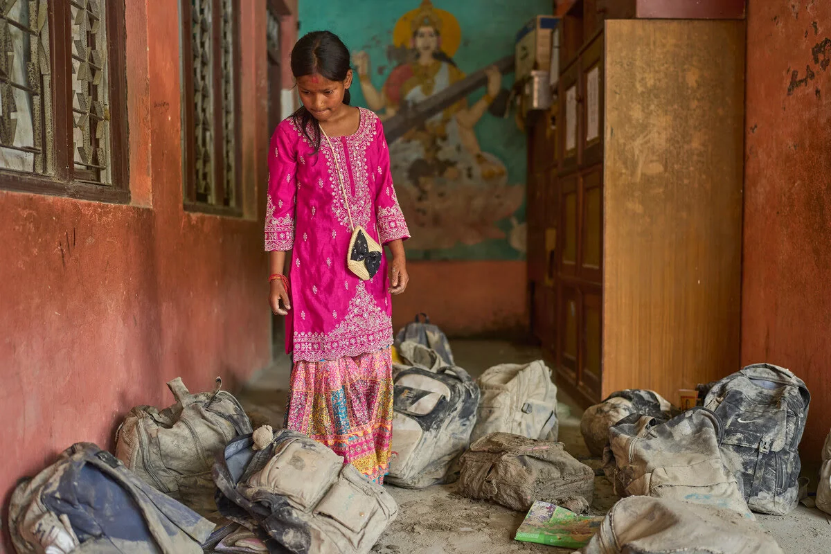 Eine Schülerin sucht nach der schweren Sturzflut in Nepal ihre Schultasche im Schlamm.