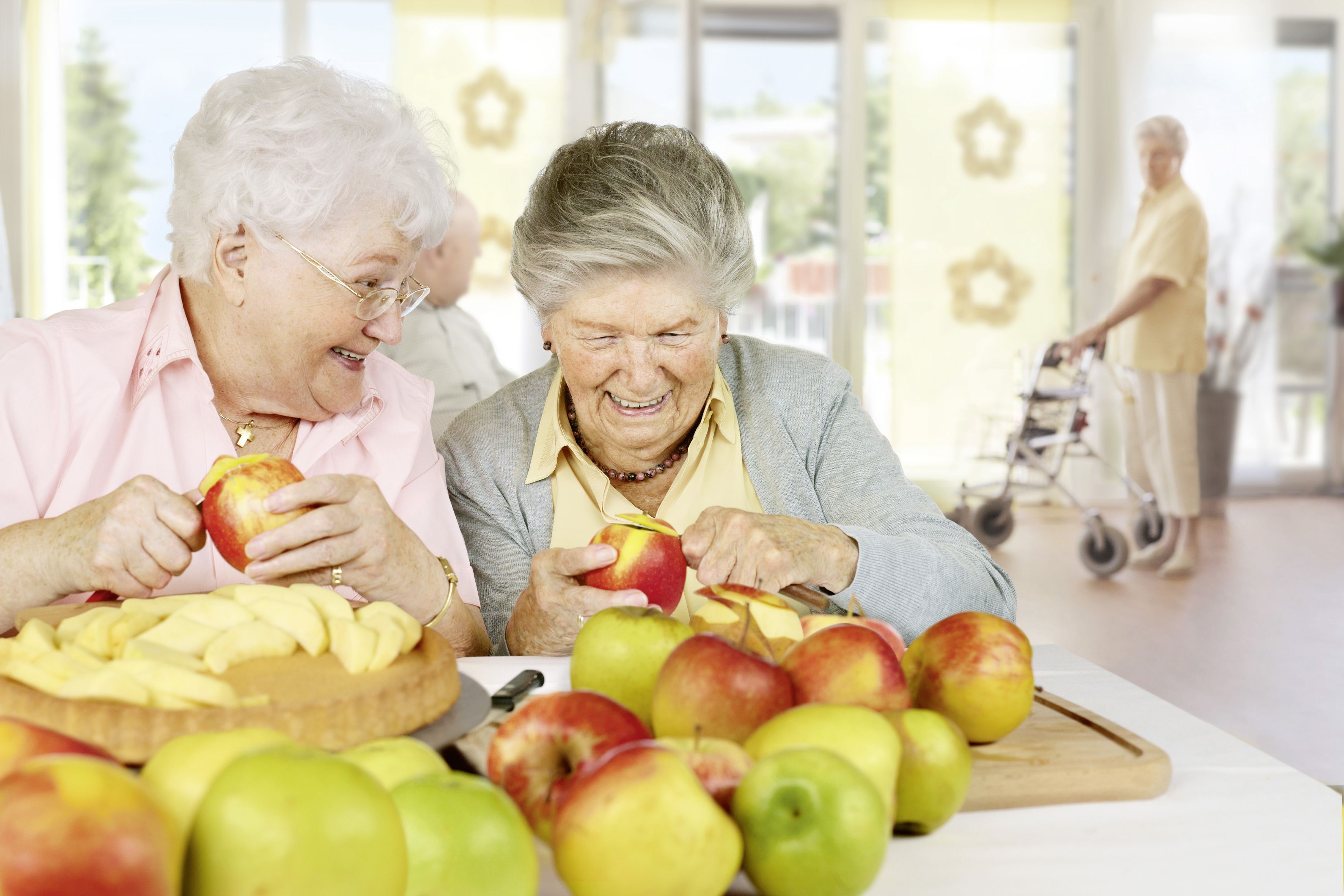 Zwei Seniorinnen schälen Äpfel