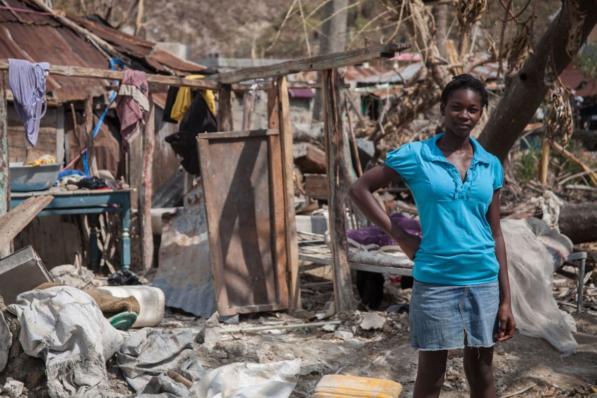 Junge Frau vor zerstörter Hütte in Tiburon in Haiti